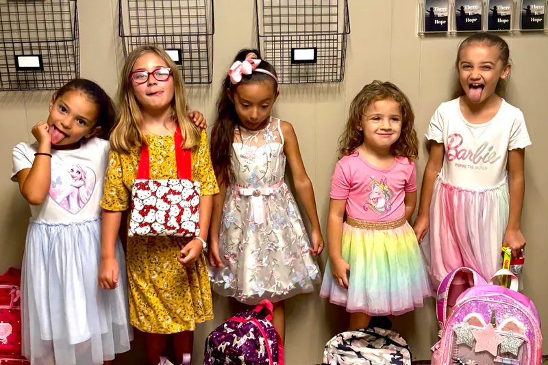 Five girls standing together with new backpacks at church.
